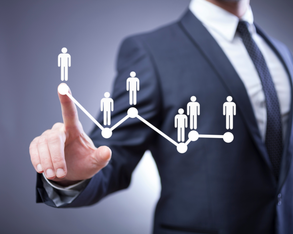 A businessman's hand interacting with a digital graph that plots human stick figures representing employee performance or growth.