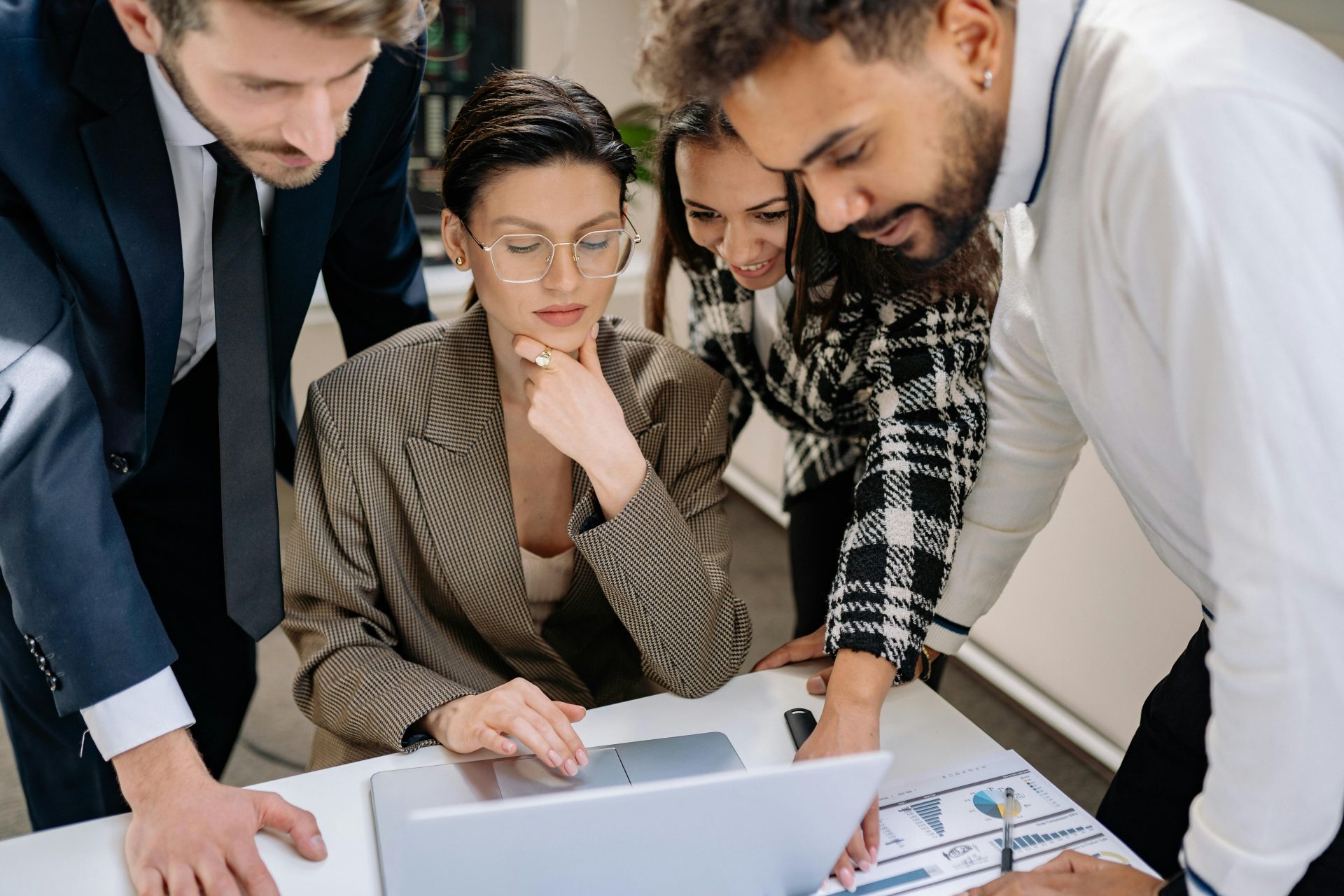 Business team collaborating around a laptop in a modern office environment.